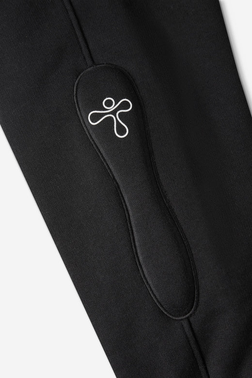 alt="detail of black jogger pants with padded embroidered detail and print"